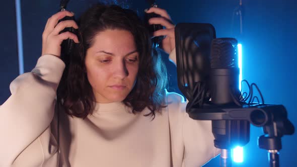 Caucasian Artist Standing Near the Microphone in the Music Studio Wearing Headphones