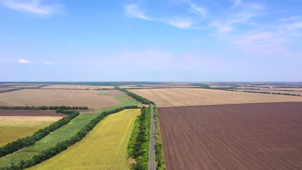 Highway among farm fields. Autumn agricultural fields. Aerial view.