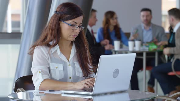 Hispanic businesswoman using laptop computer in office lobby