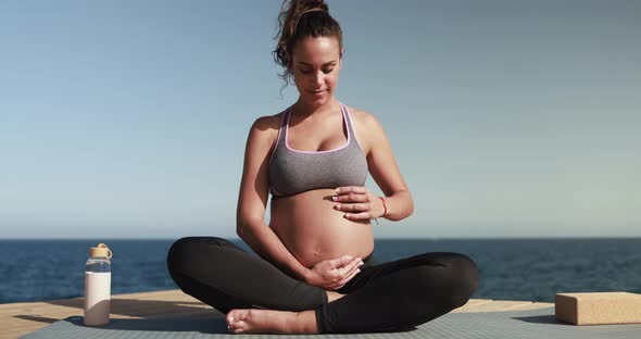 Pregnant woman doing yoga outdoor - Meditation and maternity concept for an healthy lifestyle alt