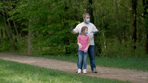Father and Daughter in Medical Masks and Rubber Gloves Spin in the Spring Park. The Concept of