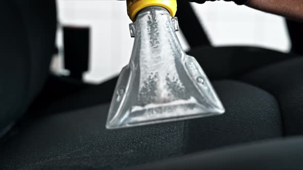 Working cleaner at car wash. Cleaning a seat using a professional vacuum cleaner. Slow motion alt