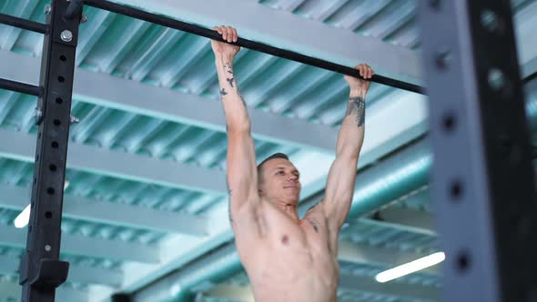 Muscular Fit Handsome Sportsman Pulling Up on Gymnastic Bar in Slow Motion Smiling alt