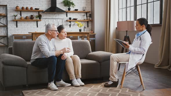 Elderly Male and His Spouse Talking to Woman Doctor About His Throat Ache During Medical alt