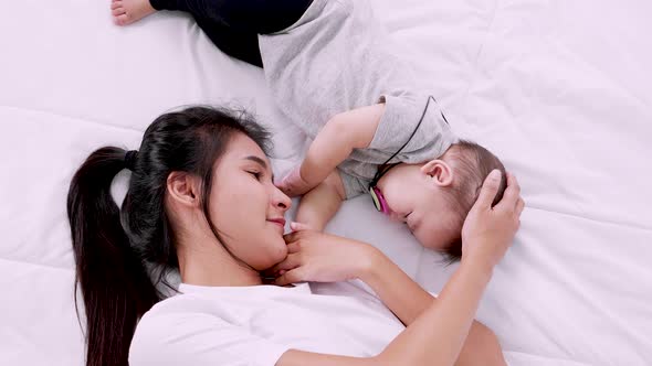 Young mom and her baby sleeping in bed together. Happy family