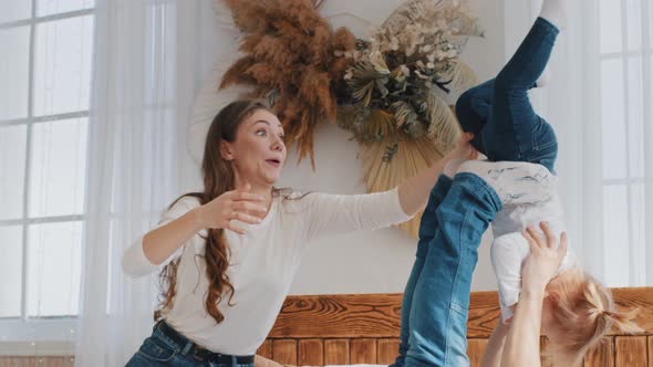 Happy Cute Small Girl Baby Playing Plane Game Having Fun with Young Father and Mother on Bed Dad alt