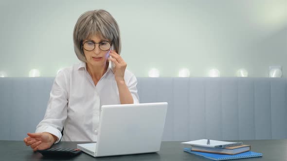 An Elderly Businesswoman Indignantly Communicates with Her Employees on the Phone and Solves