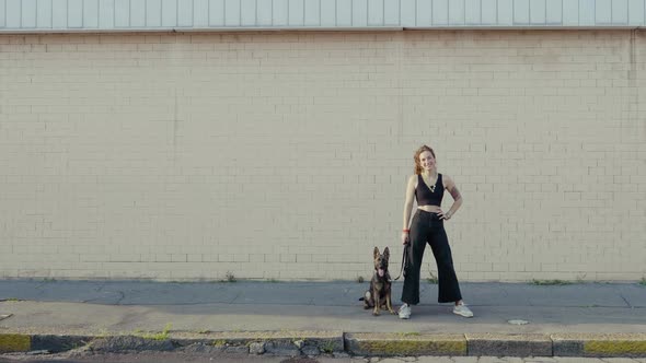 Young woman with dog in front of a wall alt