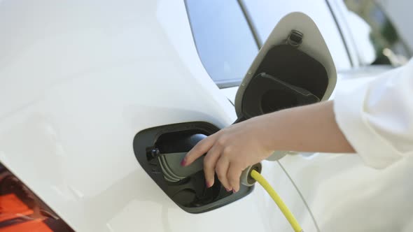Woman Opening the Electric Car's Hatchet and Plugging It in to Charge