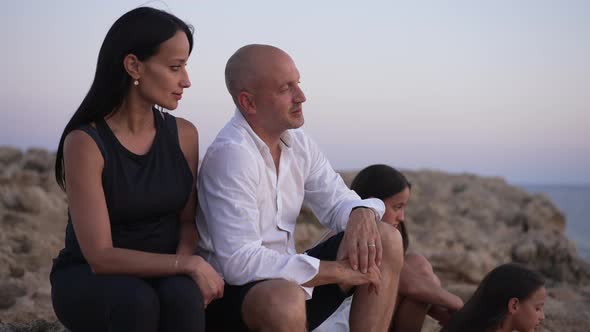 Side View Happy Relaxed Couple of Parents Talking Admiring Golden Sunset with Daughters Sitting on alt