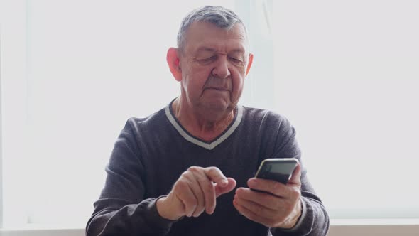 Elderly Man Dials Number in Smartphone From Home