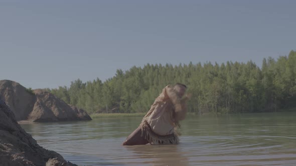 A Young Male Shaman Dances a Ritual Dance Standing Kneedeep in a River alt