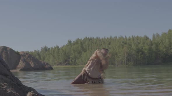 A Young Male Shaman Dances a Ritual Dance Standing Kneedeep in a River