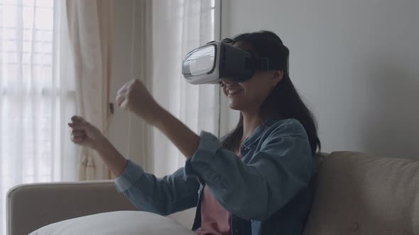 Attractive portrait young Asian woman wearing VR headset in the living room playing a game.