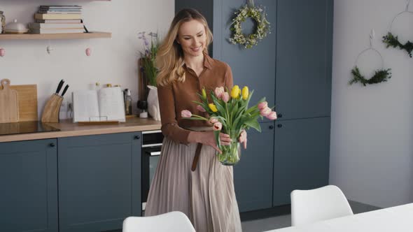 Caucasian woman putting fresh tulips into the vase. Shot with RED helium camera in 8K. alt
