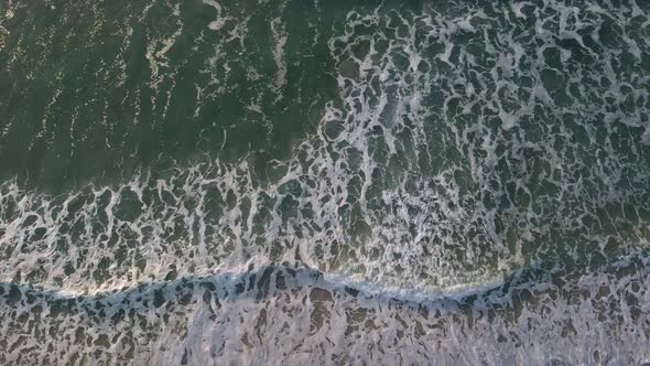 Waves breaking cleanly towards the beach at a surf spot. White horses visible behind the wave with a alt