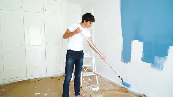 young man painting wall in blue color alt