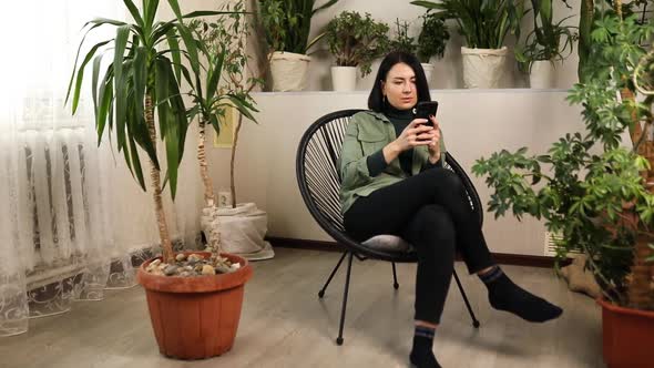 Woman Chatting Using Smartphone Sitting on Armchair at Home