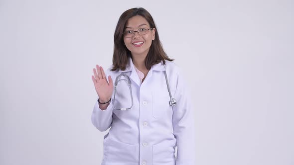 Happy Young Beautiful Asian Woman Doctor Waving Hand alt