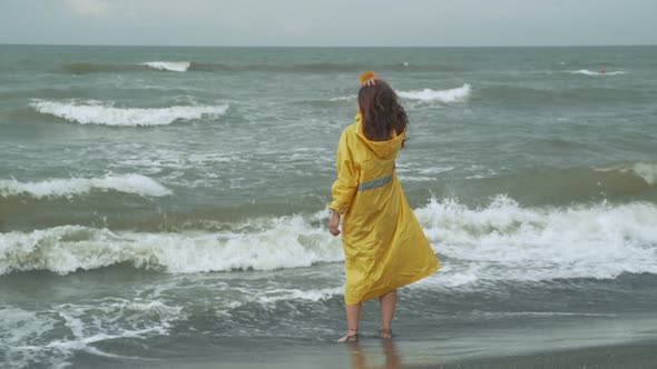 Woman In Raincoat Standing In Waving Sea