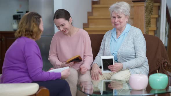 Laughing Multigenerational Caucasian Women Watching Photos Talking Resting Indoors on Weekend alt