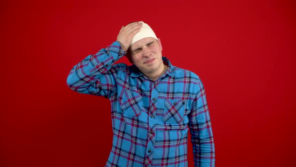 The Young Man Has a Bandage on His Head He Is Holding It with His Hands Because of the Pain alt
