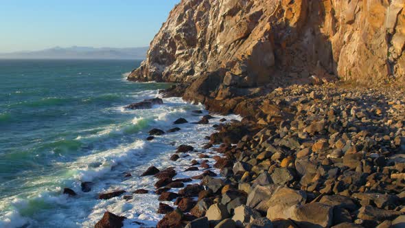 Flying Over Waves Crashing on Rocky Shore at Morro Rock Morro Bay California alt