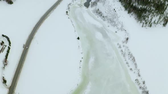 Cars Driving In A Narrow Road Across A Frozen Lake And Snow Covered Forests In Haugastol Norway - ae alt