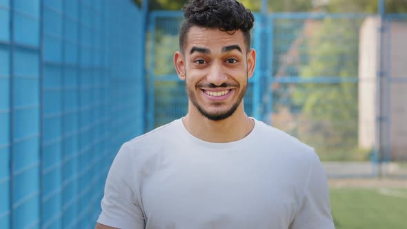 Attractive Middle Eastern Indian Young Male Athlete Standing in Stadium in Sportswear Waving Hand alt