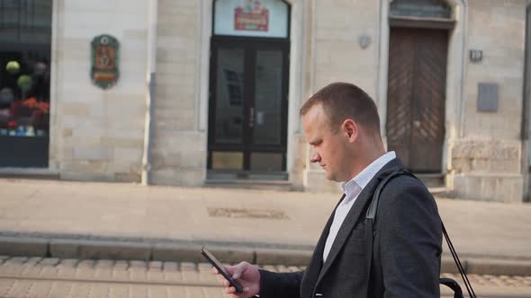 The Guy Walks Through the Ancient City and Writes a Message on a Smartphone