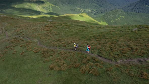 Two hikers with backpacks are walking along mountain range in Carpathian mountains. alt