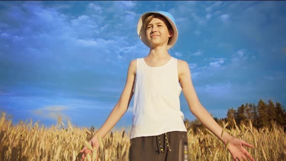 Happy Boy in a Blue Hat Walks on a Golden Wheat Field on a Sunny Day Have Fun