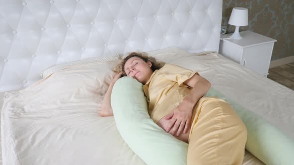 Young Pregnant Woman Sleeping On Maternity Pillow In Bed
