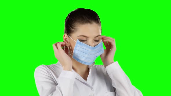 Young Doctor Putting on Health Mask. Green Screen. Closeup alt