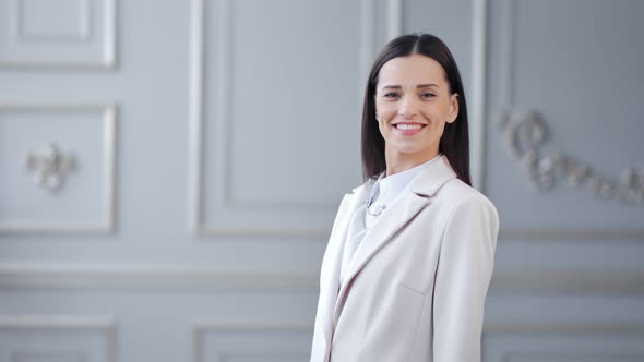 Portrait of Smiling Young Businesswoman Posing and Looking at Camera in White Luxury Background alt