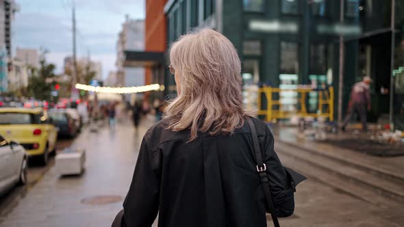 Stylish Friendly Mature Woman Walking in the City After Work alt