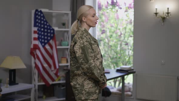 Confident Beautiful Female Soldier in Uniform Looking Out the Window Turning to Camera Smiling alt