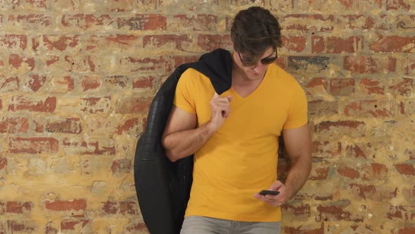 Caucasian man using a smartphone on a brick wall alt