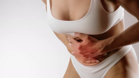 Woman Touching Her Stomach Because of Stomach Pain alt