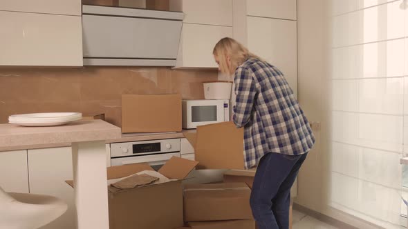 A Woman Puts White Plates in Cardboard Boxes