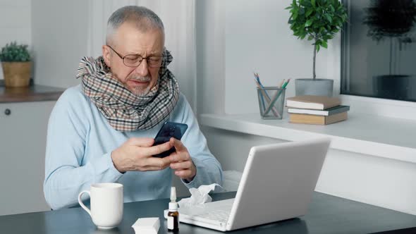 A Sick Person Sits at a Table at Home and Suffers From the Flu and a High Fever