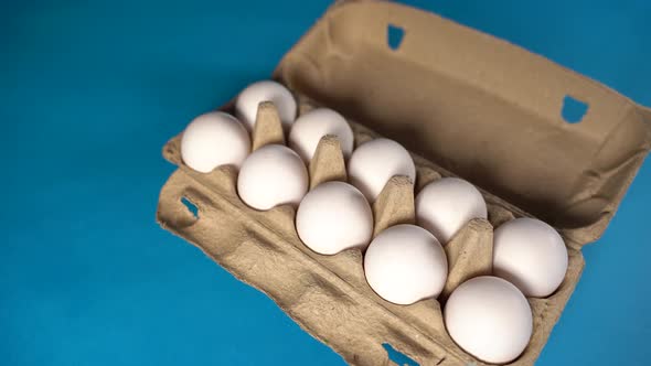 Farm Raw Fresh White Chicken Egg in an Egg Box on a Blue Background alt