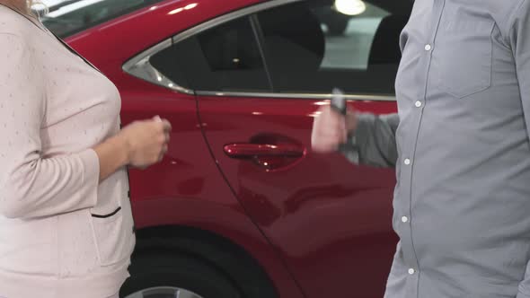 Cropped Shot of a Woman Receiving Keys To Her New Auto at the Dealership alt