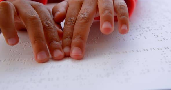 Close-up of blind Asian schoolboy hand reading a braille book in classroom at school 4k alt