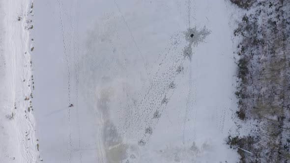 A Fisherman Walking Alone Fishing Holes Drilled in Ice for Winter Fishing