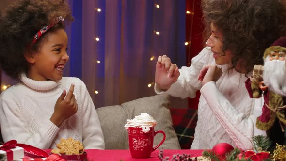 African American Mom and Little Daughter in White Sweaters Have Fun and Taste Whipped Cream with alt
