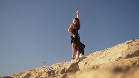 Wide Shot of Gorgeous Free Caucasian Ballet Dancer Standing on Yellow Rocky Coast with Clear Blue alt