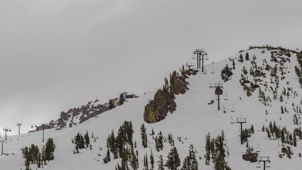 Ski mountain looking at skiing and snowboarding on snow with chairlift and clouds time lapse alt