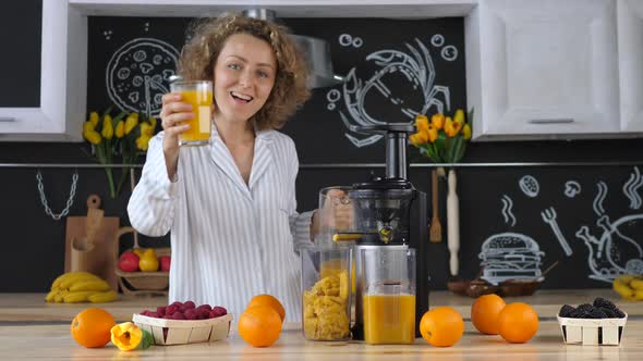 Beautiful Young Woman In Kitchen Squeezing Orange Juice With Juicer alt
