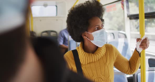 African american businesswoman with face mask standing in bus alt
